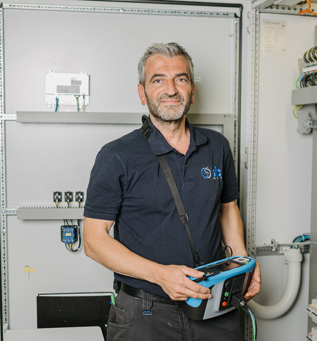 SFC-Prüftechniker mit Messgerät an einem geöffneten Schaltschrank